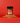 A bottle of Chili Crisp SaladSprinkles nestled in a little pile of salad sprinkles on a red background.
